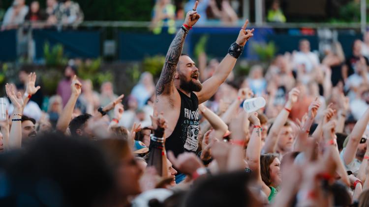 Man on someone's shoulders in Eden Sessions crowd with his arms in the air