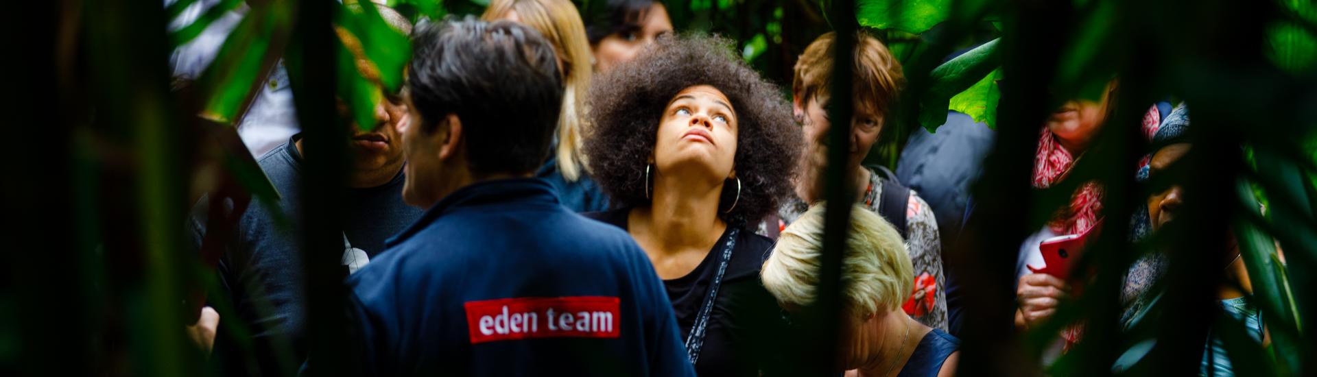 Woman looking up at plants as an Eden team member gives a tour