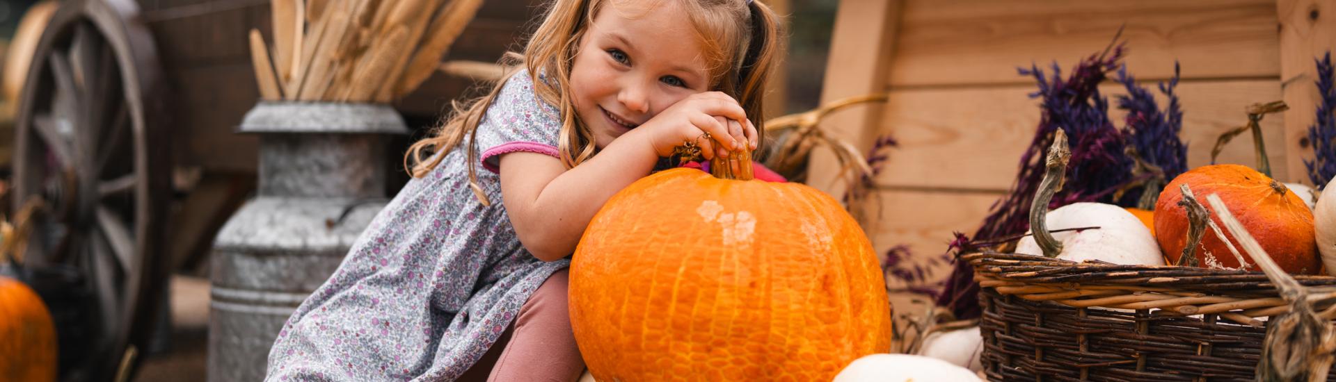 Girl leaning against a pumpkin display